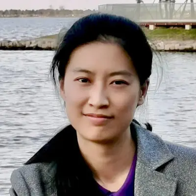 A photo of Creator Kirsty Wan standing in front of a lake