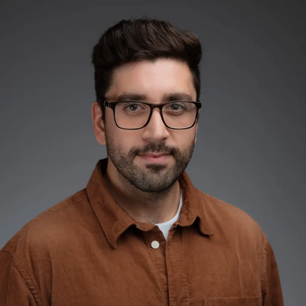 A photo of Yasir Bakki smiling against a grey background.
