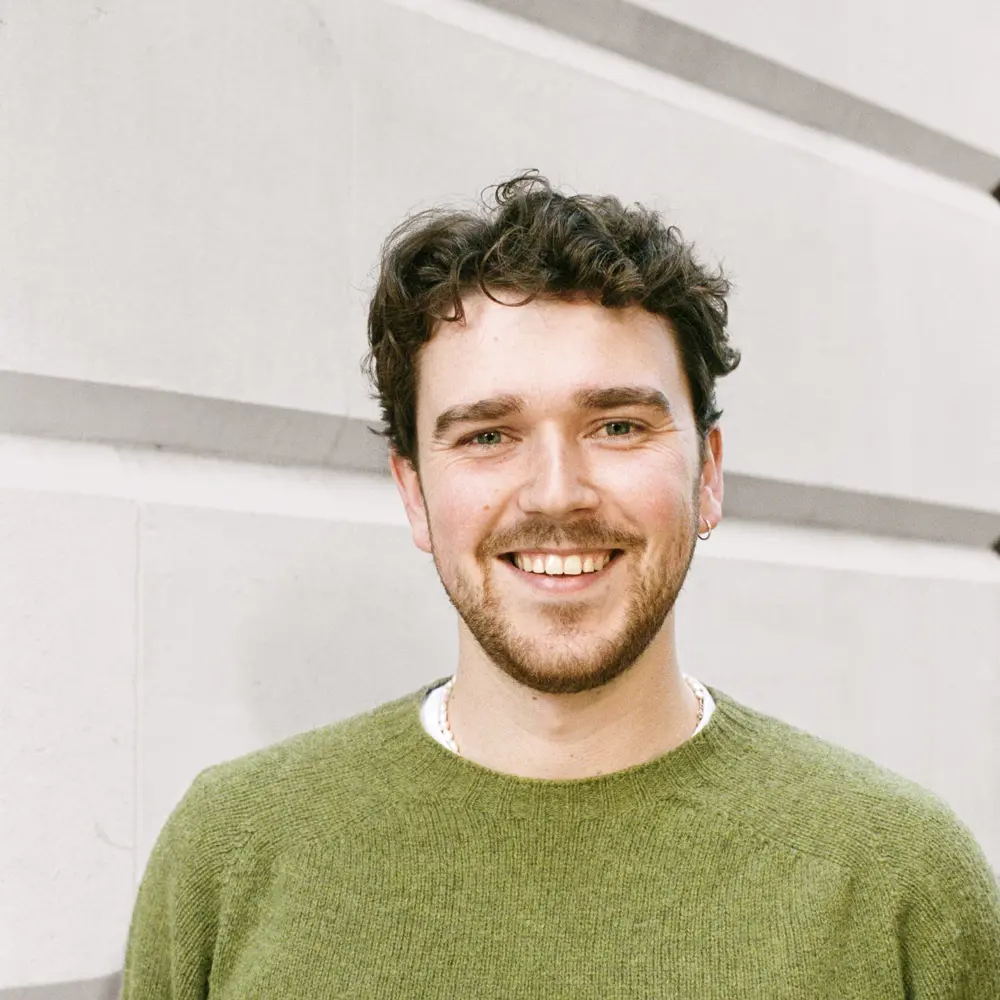 A photo of George Horner smiling against a white call. 