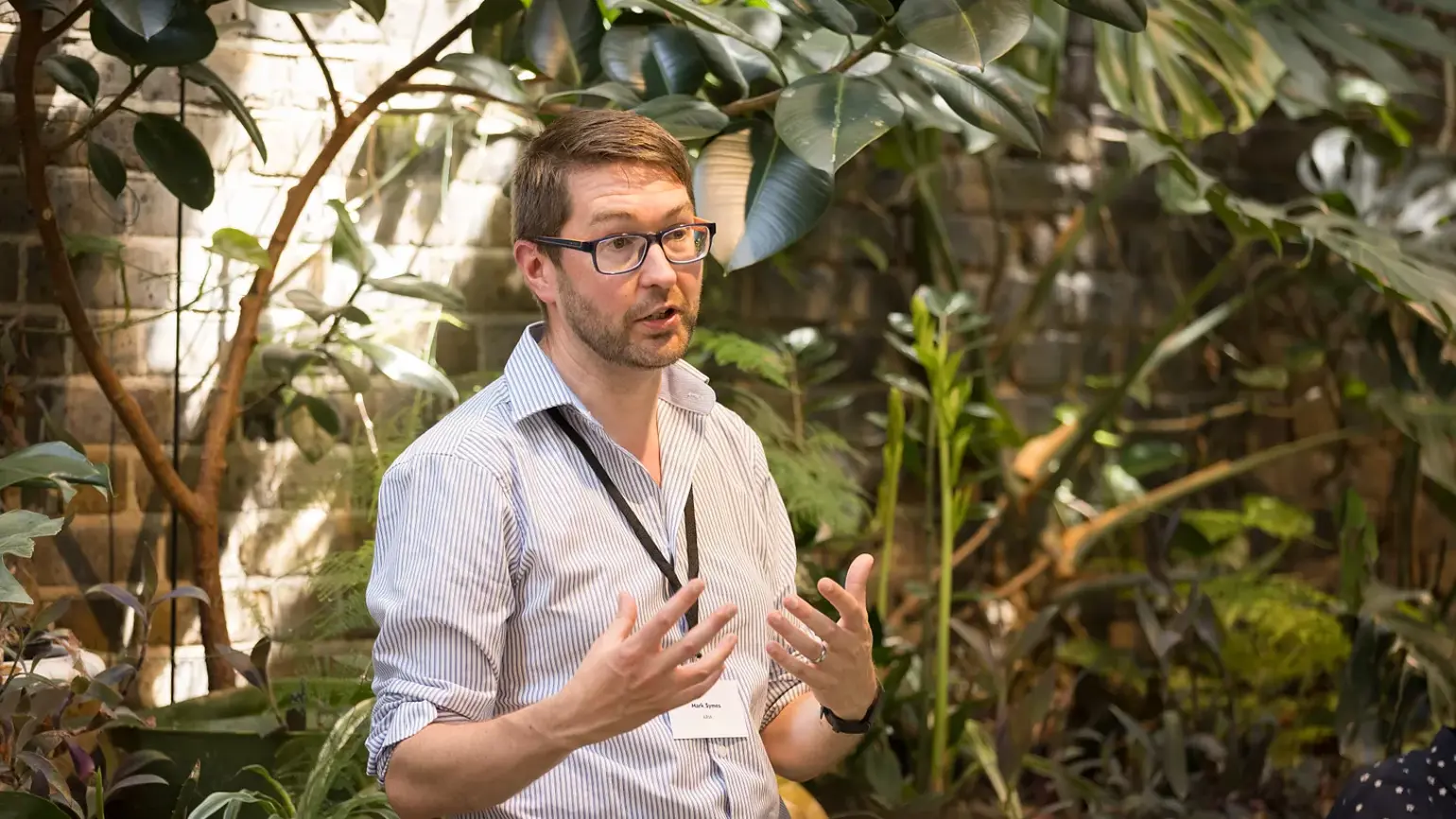 A photo of Mark Symes speaking at an event.