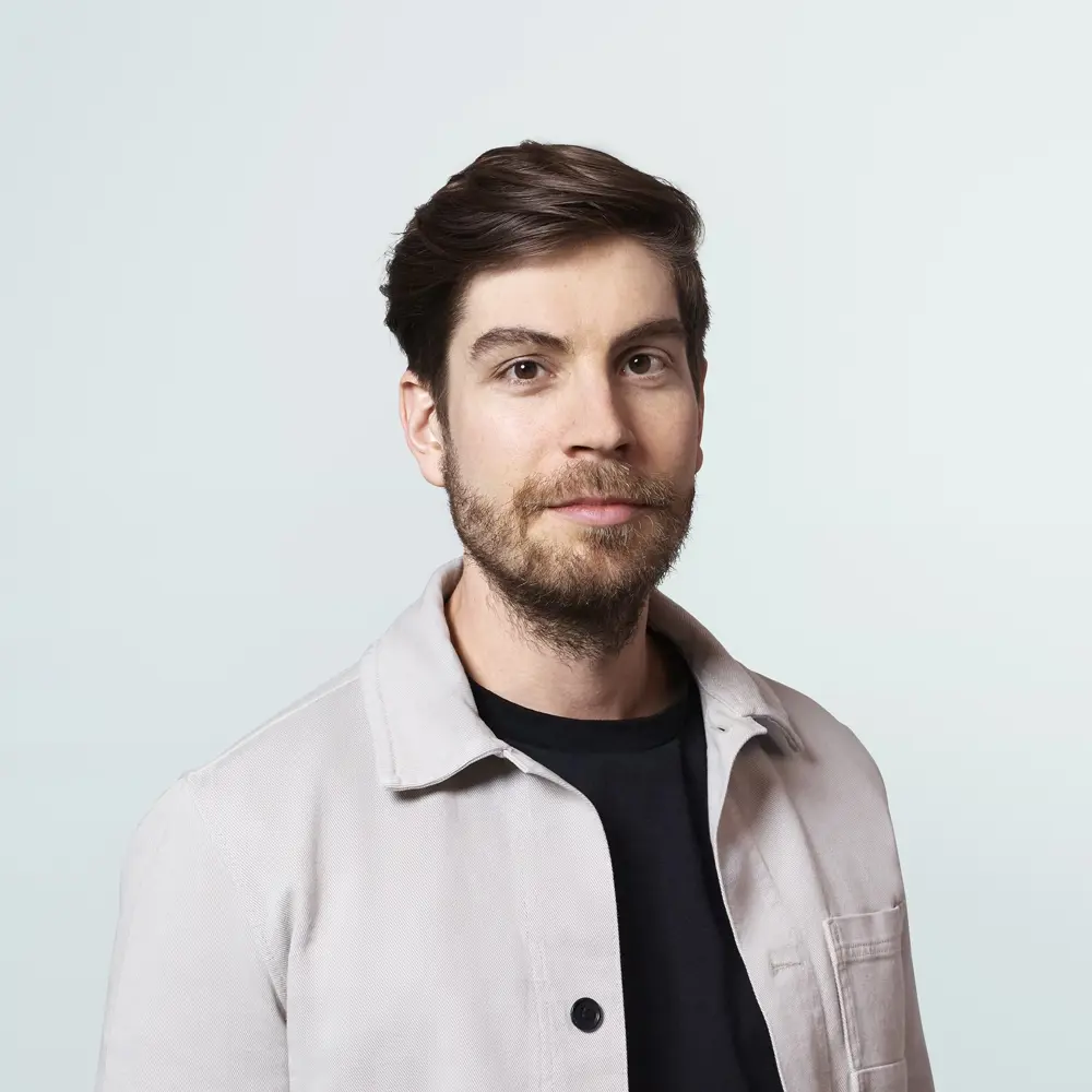 Headshot of Max Jaderberg against a light blue background